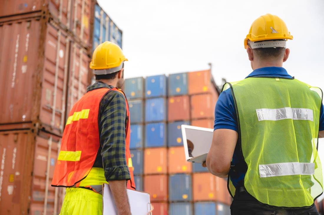 2 men in PPE in a terminal yard reviewing container placement