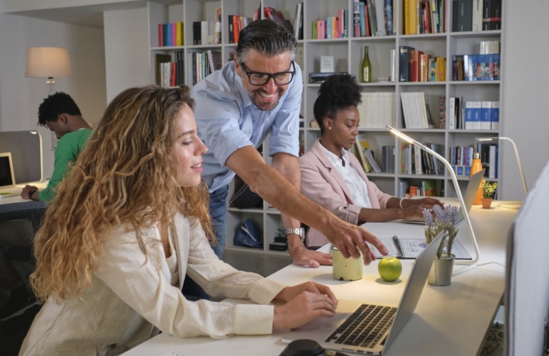 coworkers sitting together at a desk going over data together on a laptop