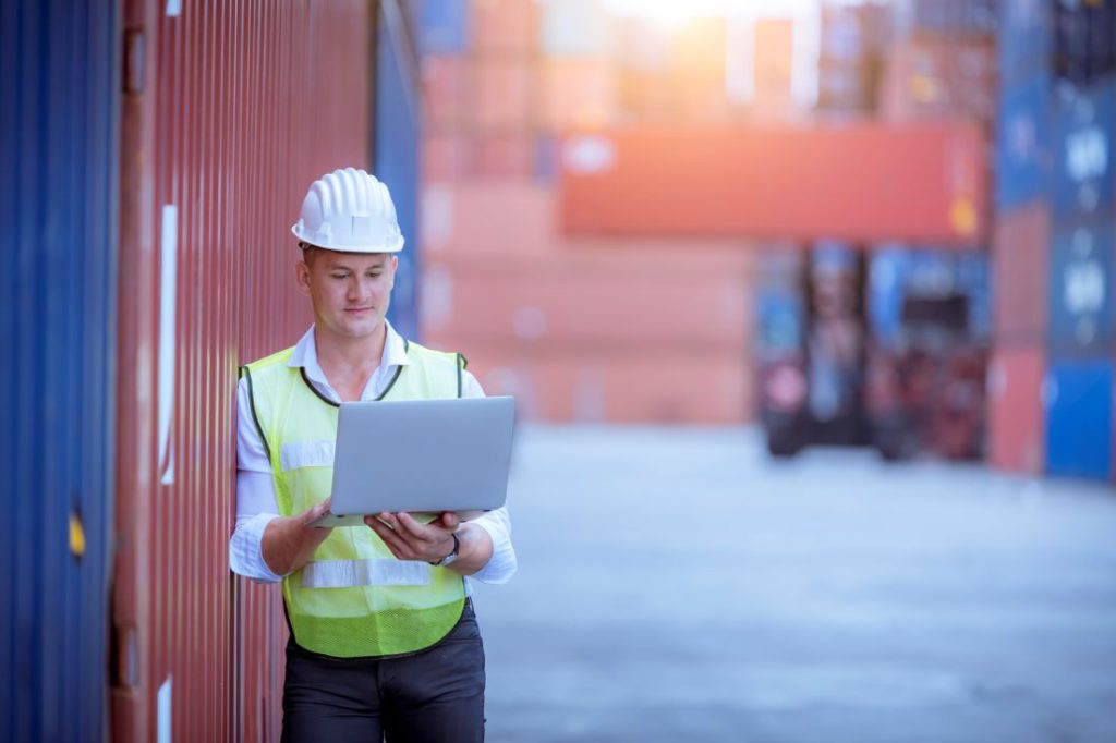 a terminal operator standing in a shipping yard utilizing cloud-based capabilities
