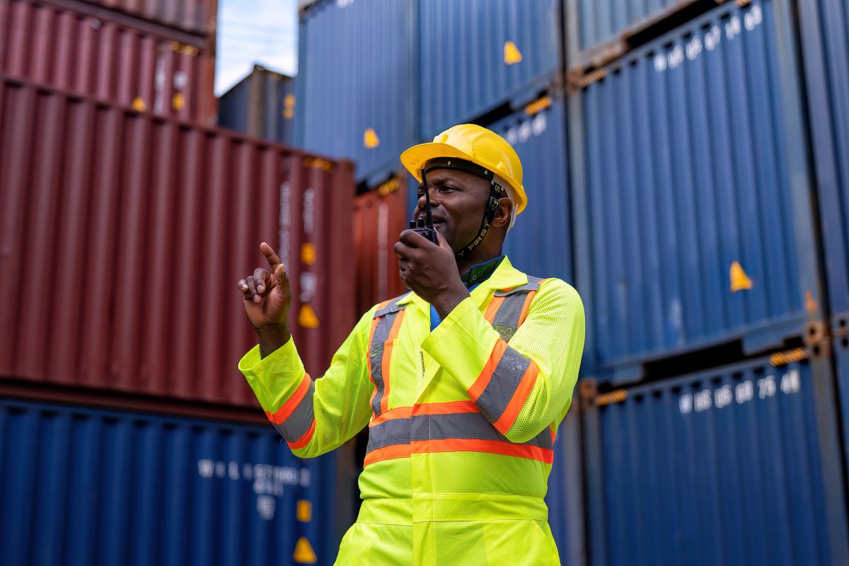 Worker in container terminal yard using a walkie-talk to check quantity