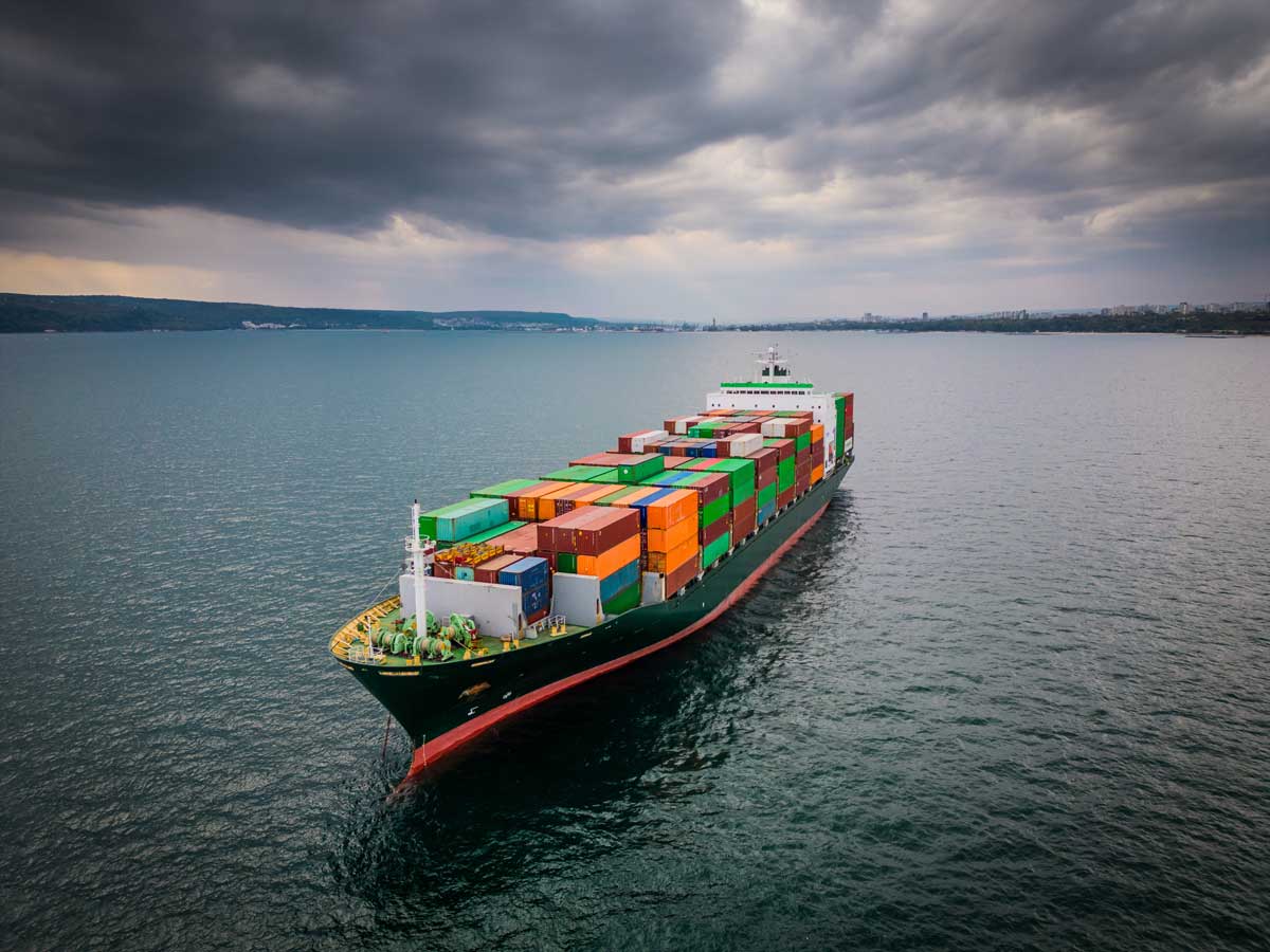 cargo ship loaded with colorful shipping containers sailing on calm waters under a cloudy sky